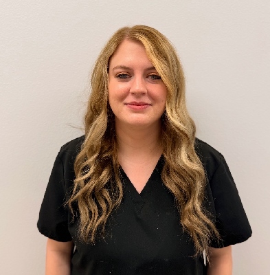Katie, Scheduling Coordinator at Graf Orthodontics, smiling in a black scrub top against a neutral background.
