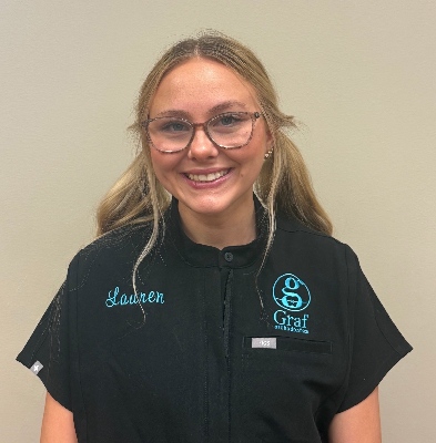 Lauren, Records Tech at Graf Orthodontics, smiling in a black uniform with the Graf logo and her name embroidered, showcasing the friendly team atmosphere in Northwest Louisiana.