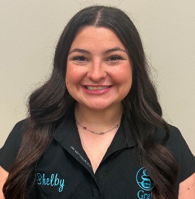 Shelby, Clinical Assistant at Graf Orthodontics, smiling in a black staff shirt with the practice logo.