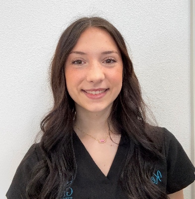 Kelsey, Clinical Assistant at Graf Orthodontics, smiling in a black uniform against a light background.