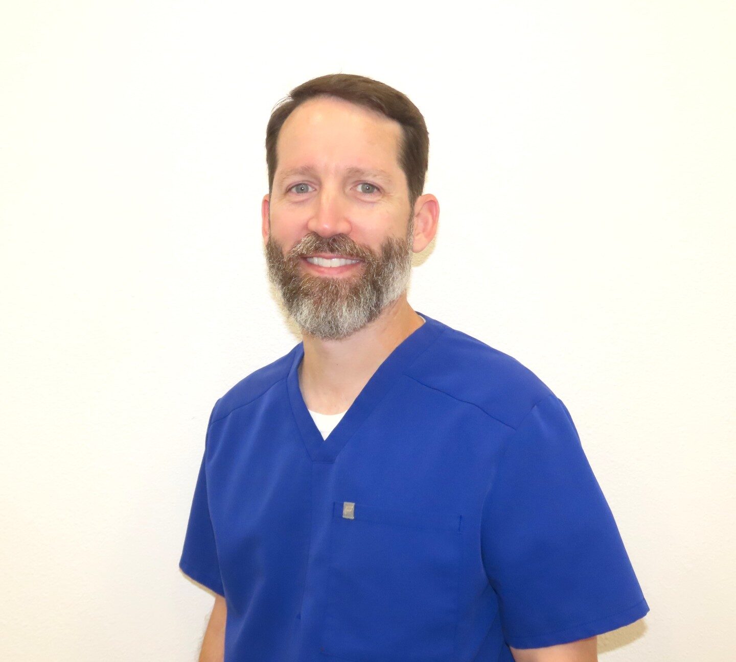 Dr. Chapman, board-certified orthodontist at Graf Orthodontics, smiling in blue scrubs.